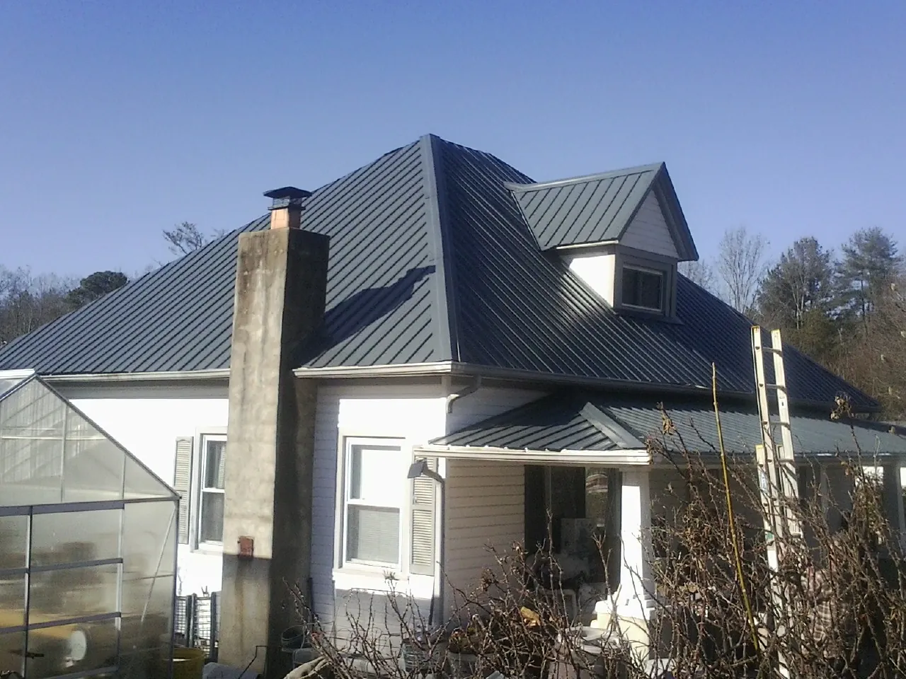 Dark blue standing seam metal roof on a white farmhouse with dormer — Slate & Tile Roof Repair by Roofing Brothers in Elora