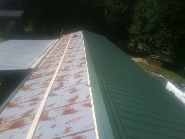 Old rusted panels beside newly installed green metal roofing — Wind Damage Roof Repair by Roofing Brothers in Elora