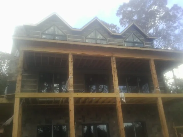 Dormers and porch framing on a large log home under construction — Roof Coating work by our crew in Elora
