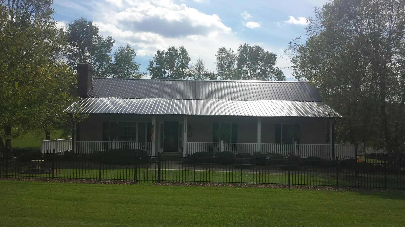 Gray metal roof on a brick ranch with a full width front porch — Gutter Guard Installation work by our crew in Elora