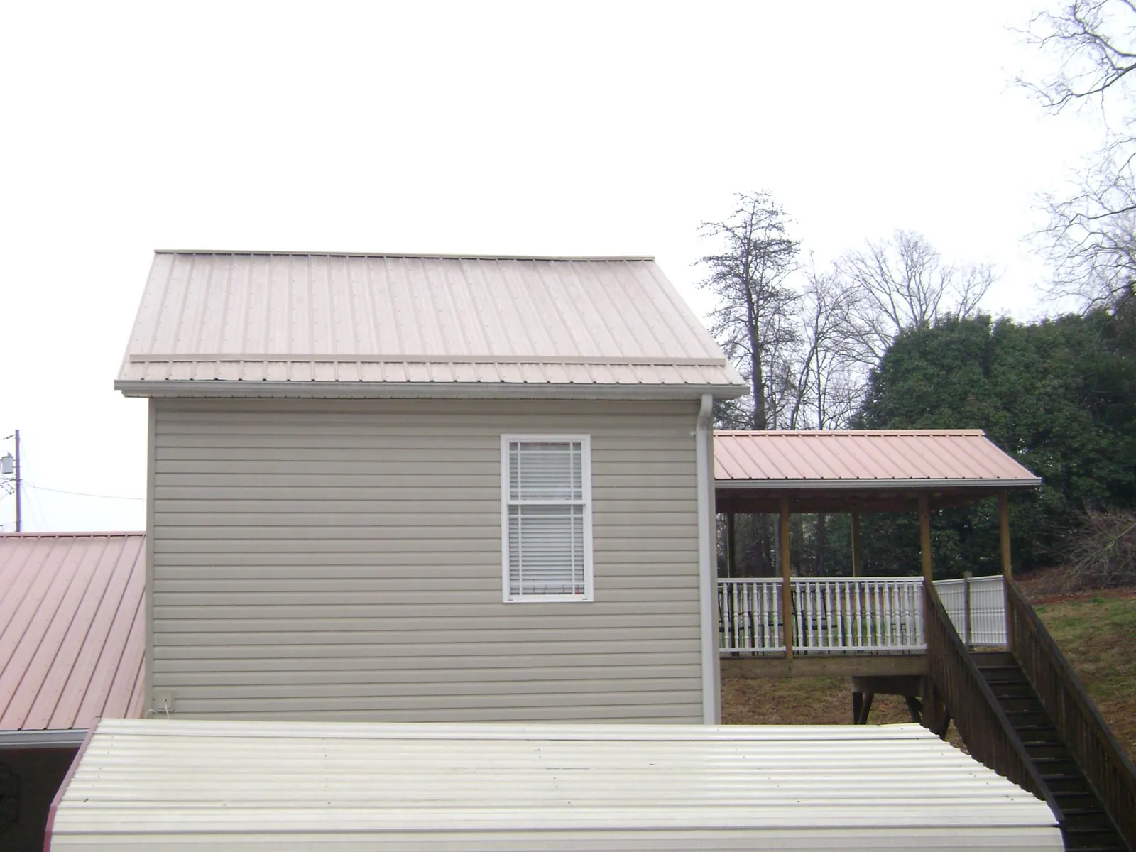 Tan metal roofs on a two story addition and attached porch, from a Roof Replacement job in Elora