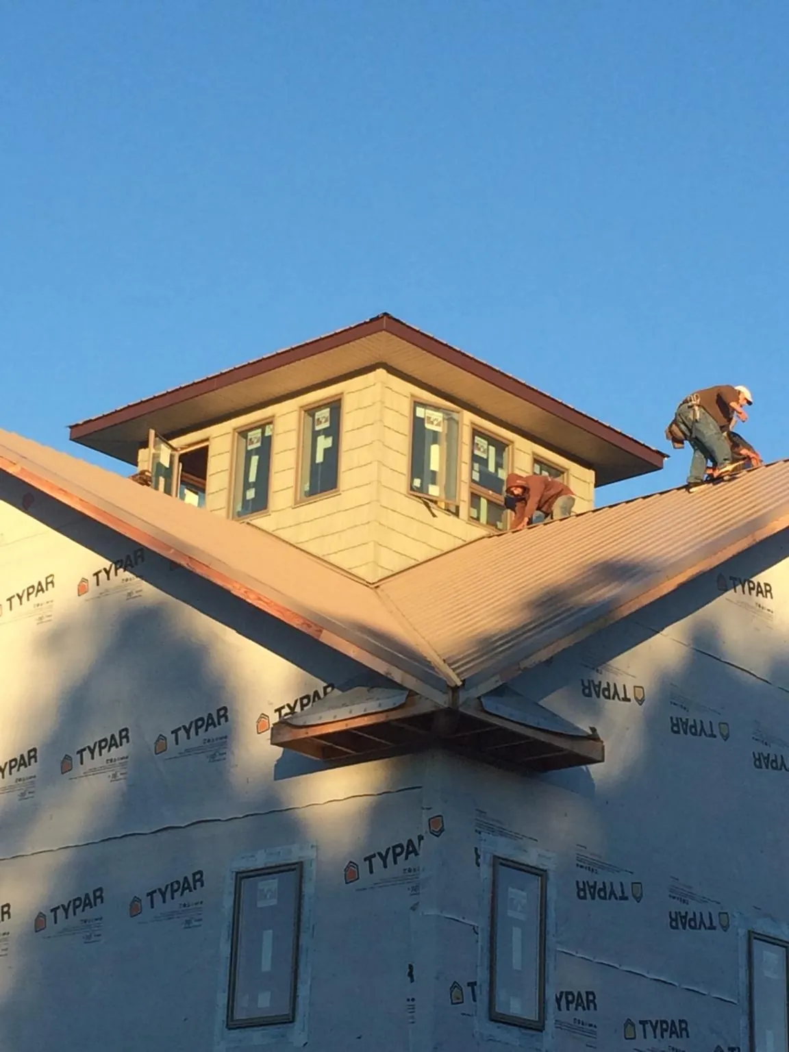 Roofers working around a rooftop cupola on a new metal roof at sunset — Roof Waterproofing in Elora by Roofing Brothers